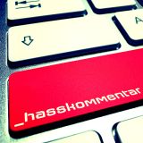PC Tastatur mit einem roten Button und der Aufschrift Hasskommentar